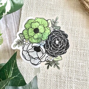 May include: A sticker featuring a bouquet of flowers with black, white, and green petals. The flowers are arranged in a cluster with leaves and stems.