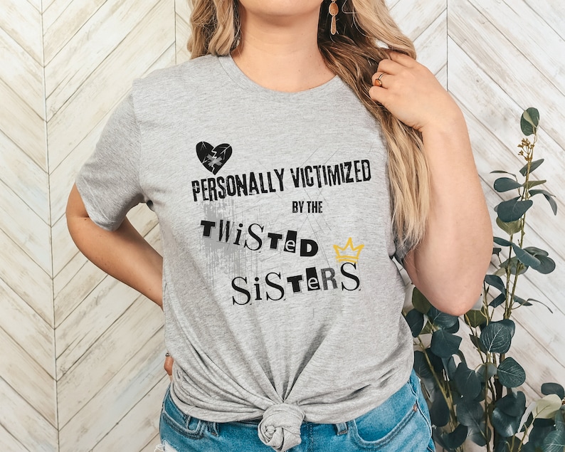 May include: Gray t-shirt with a black broken heart and the text "PERSONALLY VICTIMIZED BY THE TWISTED SISTERS" in black with a gold crown.