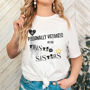 May include: White t-shirt with a black broken heart and the text "PERSONALLY VICTIMIZED BY THE TWISTED SISTERS" with a gold crown.