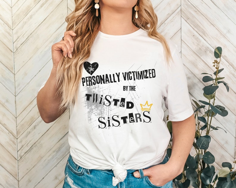 May include: White t-shirt with a black broken heart and the text "PERSONALLY VICTIMIZED BY THE TWISTED SISTERS" with a gold crown.