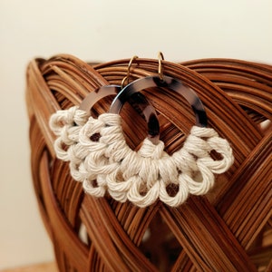 May include: A pair of handmade earrings with a white macrame design and tortoise shell hoop accents.