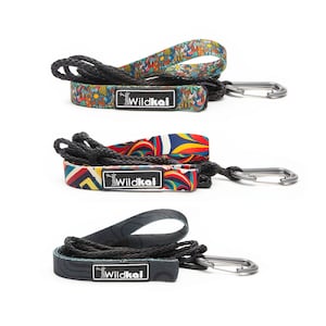 May include: Three colorful dog leashes with a black rope and a silver clip. Each leash has a different patterned fabric with the word "Wildkai" printed on it.