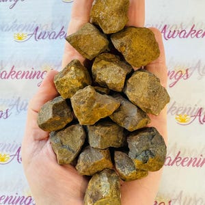 May include: A collection of 15 brown and gold tumbled stones. The stones are various sizes and shapes, with some having a rough texture.