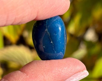 May include: A smooth, polished blue agate stone, shaped like an oval, with a light blue vein running through it.
