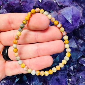 May include: A yellow, orange, and white agate gemstone bracelet with small round beads.
