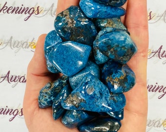 May include: A hand holding a collection of blue and grey tumbled stones. The stones are smooth and have a speckled appearance.