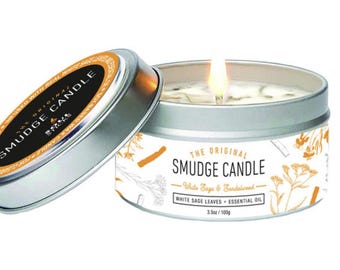 May include: A white candle with a silver lid and a label that reads "The Original Smudge Candle - White Sage & Sandalwood - White Sage Leaves + Essential Oil - 3.5oz / 100g"