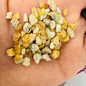 May include: A small pile of white and yellow tumbled stones. The stones are small and irregular in shape.