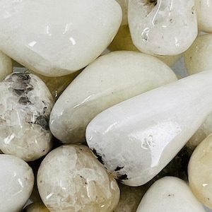 May include: A collection of white tumbled stones with a smooth, polished finish. The stones have a milky white color with subtle variations in texture and translucence.