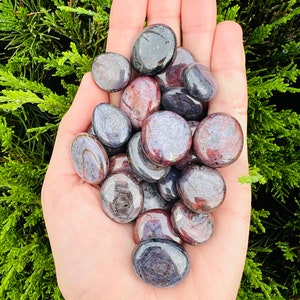 May include: A collection of tumbled stones in shades of purple, pink, and black. The stones are smooth and polished, with a variety of patterns and textures.
