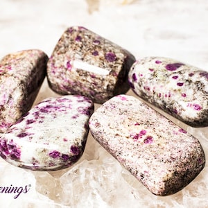 May include: Five tumbled stones with a white base and pink and gray speckles. The stones are smooth and polished.