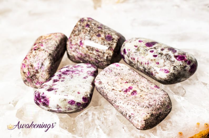 May include: Five tumbled stones with a white base and pink and gray speckles. The stones are smooth and polished.
