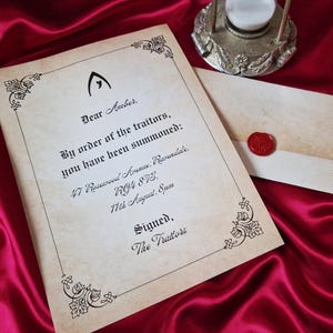 May include: A vintage-style invitation on aged paper with ornate corner designs. The text reads "Dear Amber, By order of the traitors, you have been summoned." A matching envelope with a red wax seal is next to the invitation.