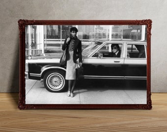 May include: A black and white photo of a couple in a vintage car. The woman is wearing a dress and a jacket, and the man is wearing a suit. The car is a classic sedan with a long hood and a large trunk.