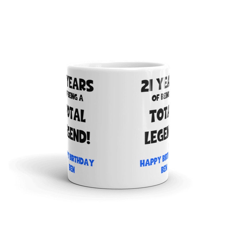 K&ouml;nnte beinhalten: Wei&szlig;e Keramiktasse mit schwarzem Text, der "21 Years of Being a Total Legend!" und "Happy Birthday Ben" in blauer Schrift lautet.