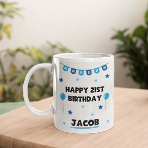 May include: White ceramic mug with a blue and white design. The mug has a blue banner with the text "Happy 21st Birthday" and the name "Jacob".