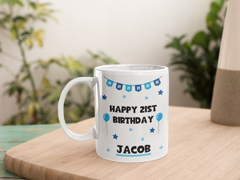 May include: White ceramic mug with a blue and white design. The mug has a blue banner with the text "Happy 21st Birthday" and the name "Jacob".