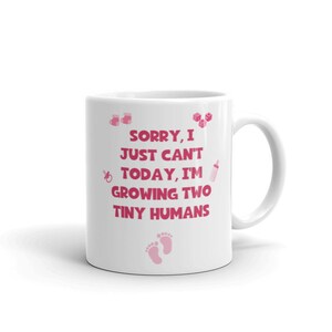 K&ouml;nnte beinhalten: Wei&szlig;e Keramiktasse mit rosafarbenem Design. Die Tasse tr&auml;gt den Text "Sorry, I just can't today, I'm growing two tiny humans".