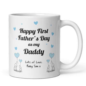 Puede incluir: Taza de cer&aacute;mica blanca con un dise&ntilde;o azul y negro. La taza dice "Happy First Father's Day as my Daddy" con dos corazones azules y dos elefantes sosteniendo globos azules. El texto "Lots of Love, Baby Tom x" est&aacute; en la parte inferior.