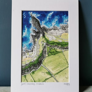 May include: An aerial watercolor painting of the Giant's Causeway in County Antrim, Northern Ireland. The painting shows the rocky coastline and the surrounding green fields. The text "giant's causeway, co. antrim" and "m.ogbly" are written in the bottom corners of the painting.