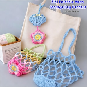 May include: A collection of handmade crochet items, including a blue mesh bag, a rainbow-colored mesh bag with a flower, and a blue seashell pendant. A pink star-shaped pendant and a ball of yarn are also visible. The text reads "2in1 Foldable Mesh Storage Bag Pendant Crochet Pattern."