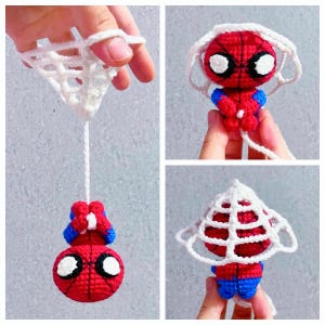 May include: A small, handmade crochet amigurumi figure of a red and blue superhero character with large white eyes. The figure is attached to a white crocheted web structure, showing the character hanging upside down and also standing upright.