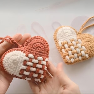 May include: Two crocheted hearts, one in a light brown and white color combination and the other in a red and white color combination. Both hearts have a woven pattern.