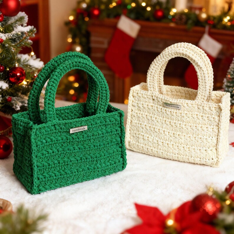 May include: Two handmade crochet tote bags. One is emerald green, the other is cream. Each has a rectangular shape, two handles, and a small metal tag that reads "handmade". The bags are on a white surface with Christmas decorations in the background.