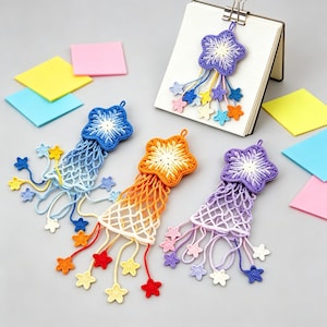 May include: Four handmade crochet star bookmarks with attached netting and dangling mini stars. One is blue, one is orange, one is purple, and one is attached to a notebook. Each features a gradient color scheme with white centers and multi-colored accents.