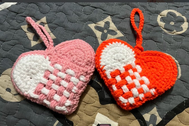 Peut inclure: Deux ornements en forme de c&oelig;ur en crochet, l'un rose et blanc, l'autre orange et blanc. Les deux ont un motif tiss&eacute; et une boucle pour accrocher.