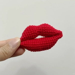 Könnte beinhalten: Eine rote gehäkelte Lippenform, ein handgefertigtes Kunsthandwerk.