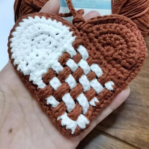 Peut inclure: Un c&oelig;ur en crochet marron et blanc avec un motif tiss&eacute;. Le c&oelig;ur est tenu dans une main.