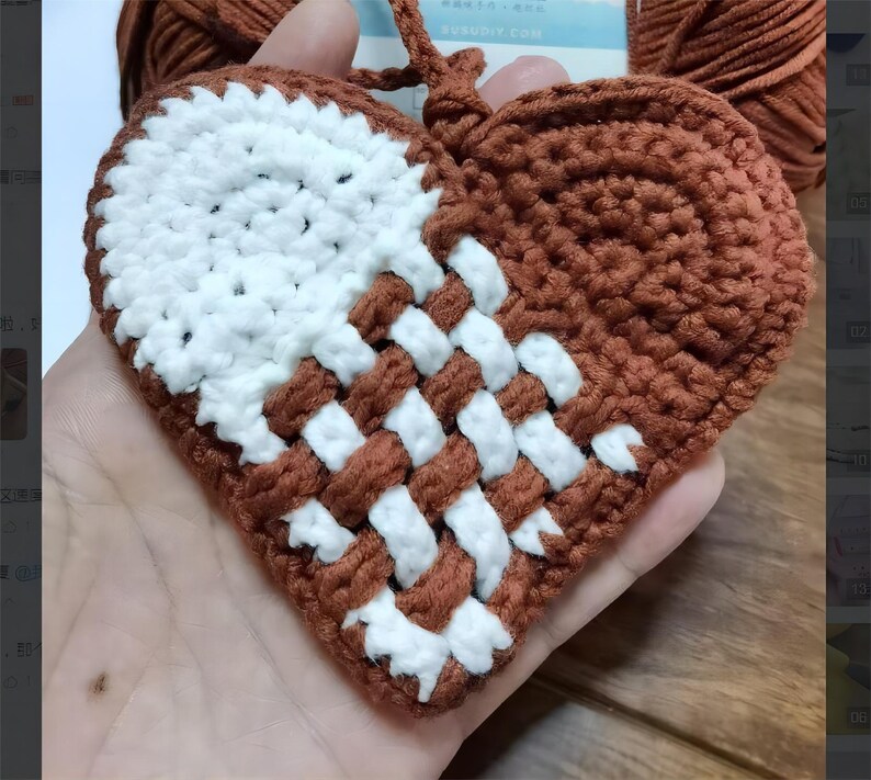 Peut inclure: Un c&oelig;ur en crochet marron et blanc avec un motif tiss&eacute;. Le c&oelig;ur est tenu dans une main.