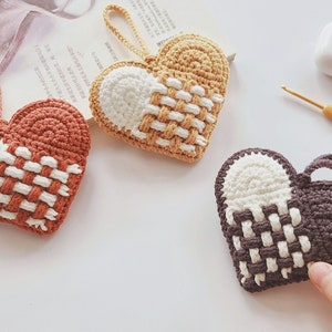 Peut inclure: Trois ornements en forme de c&oelig;ur en crochet de couleur marron, beige et gris avec des accents blancs. Chaque c&oelig;ur a un motif tiss&eacute; et une boucle pour l'accrocher.
