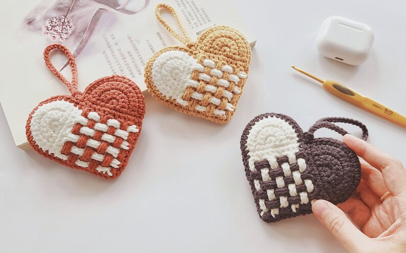 Peut inclure: Trois ornements en forme de c&oelig;ur en crochet de couleur marron, beige et gris avec des accents blancs. Chaque c&oelig;ur a un motif tiss&eacute; et une boucle pour l'accrocher.