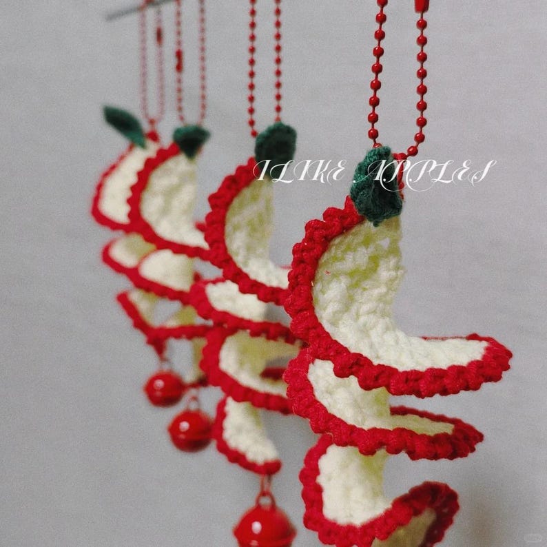May include: Crocheted spiral ornaments with red and white detailing, accented with green leaves and red ball pendants. The text "I LIKE RIPPLES" is visible. These handmade decorations are likely for holiday or seasonal use.