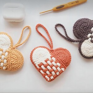 Peut inclure: Trois ornements en forme de c&oelig;ur en crochet avec du fil blanc et marron, blanc et orange et blanc et gris. Les c&oelig;urs ont un motif tiss&eacute;.