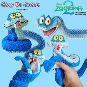 Puede incluir: La imagen presenta varias serpientes de ganchillo azules y blancas con ojos amarillos y lenguas rojas. Las serpientes están inspiradas en la película de Disney Zootopia 2. El texto de la imagen dice "Gary Del'Snake Crochet Pattern" y "Disney Zootopia 2 Only in Theaters November 26."