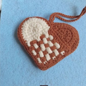 Peut inclure: Une pochette en forme de c&oelig;ur en crochet marron et blanc avec une anse en cordon marron.
