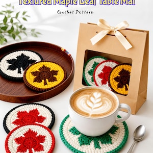 Peut inclure: Sets de dessous de verre en forme de feuille d'érable crochetées, de couleurs variées : noir, jaune, rouge et vert. Présentés avec une tasse de café et un sac cadeau. Le texte "Textured Maple Leaf Table Mat" et "Crochet Pattern" sont visibles.