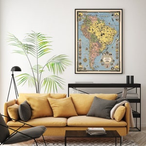 May include: A vintage-style map of South America in a black frame hanging on a white wall above a yellow sofa. The map is filled with illustrations of animals, cities, and landmarks. The map is surrounded by a decorative border.