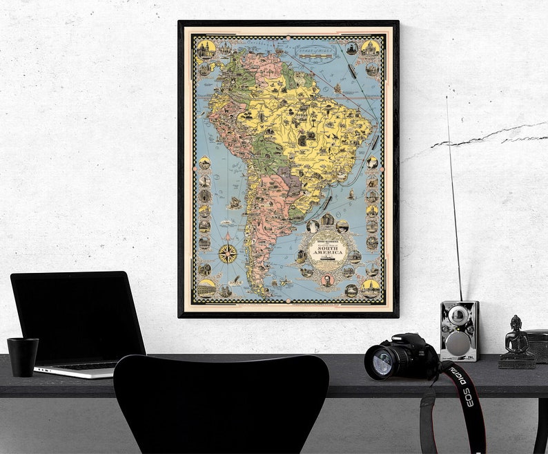 May include: A vintage-style map of South America with a black frame. The map is printed on paper with a light blue background and features various colours and illustrations. The map includes the text "South America" in a circle at the bottom.