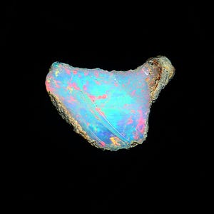 May include: A blue, green, and pink opal gemstone with a rough, natural edge. The opal is iridescent and has a variety of colors.