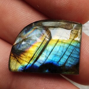 Peut inclure: Un gros cabochon de labradorite irisé avec une surface polie et lisse. La pierre présente une gamme de couleurs, notamment le bleu, le vert, l'or et le violet.