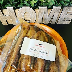 May include: A clear plastic bag filled with smoked herring fillets. The bag is labeled "Trini Treats LLC" and "Smoked Herring".