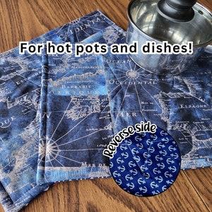 May include: Two blue and white fabric pot holders with a vintage world map design. The reverse side of the pot holders features a blue background with white anchors. The text "For hot pots and dishes!" is visible in the image.