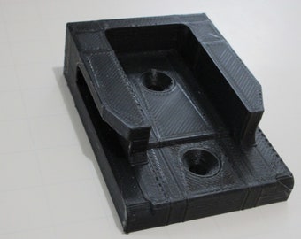 May include: A black plastic 3D printed bracket with two holes and a slot. The bracket is designed to hold a device or object.