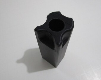 May include: A black plastic 3D printed object with a square base and a round hole in the top.