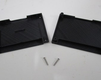 May include: Two black plastic pieces with a textured surface, likely for a small electronics project. Two small silver screws are included.