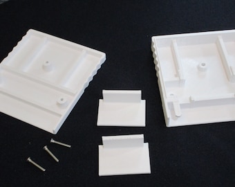 May include: White plastic case with two separate pieces, two smaller white plastic pieces, and three silver screws. The case has a rectangular shape with a raised lip around the edge.